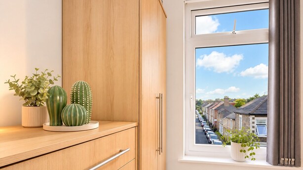 Ein Zimmer mit einem Holzkasten, einem Vorhangfenster und Blick auf eine Wohnstraße.