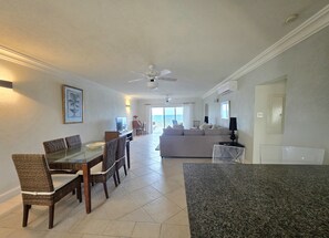 A spacious living area with a dining table, chairs, a sofa, and a ceiling fan. - 309 Mistle Cove Condos St. Lawrence Gap (Bridgetown)