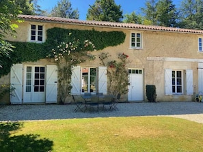 Un bâtiment à deux étages, doté d’un toit recouvert de tuiles, de volets blancs et d’une allée gravillonnée.