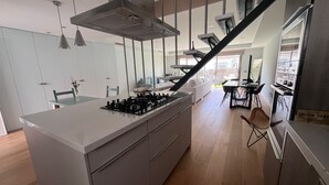 Une cuisine moderne dotée d’un îlot central, d’un coin repas avec une table et des chaises, et d’un escalier menant à un niveau supérieur.