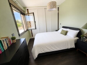 A bedroom with a bed, bedside tables, a desk with books, a window, and a hanging light fixture. - Marbella Golden Mile Townhouse 4 bedrooms, Saltwater Pools & Walk to the Beach (Marbella)