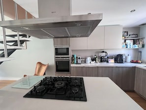 Et moderne køkken med gasblus, ovn og emfang i rustfrit stål.