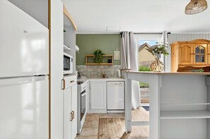Eine Küche mit weißen Schränken, einer Mikrowelle, einem Spülbecken und einem Holzschrank.