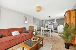Ein modernes Wohnzimmer mit einem roten Sofa, einem Holztisch und einem Essbereich mit einem weißen Tisch und Stühlen.