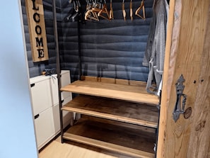 Une pièce comprenant une armoire en bois, un portant à vêtements et une étagère.