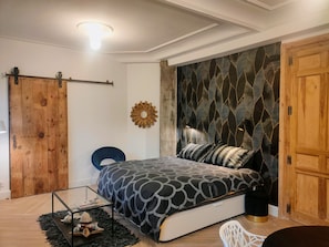 A bedroom with a bed, a wooden door, a wall-mounted decor, and a ceiling light.
