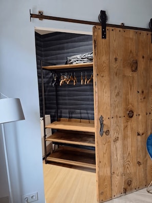 A room with a sliding wooden door, a white lamp, and a black upholstered bench.