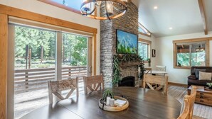 Una habitación amplia con una gran mesa de comedor, sillas de madera, una chimenea de piedra y ventanas amplias que ofrecen vistas al exterior.