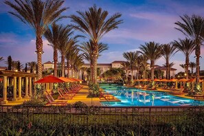 A pool area with palm trees, lounge chairs, and umbrellas. - "Location & Resort Lifestyle" Vibe (Laguna Hills)