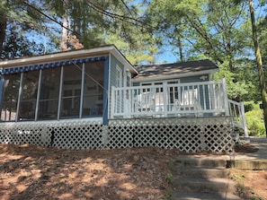 A cabin with a large windowed porch, a covered deck, and a stone pathway leading to the entrance.