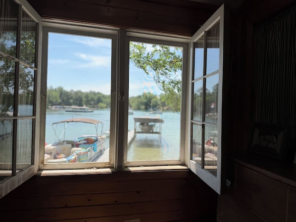 An open window with a view of a lake, boats, and docked boats.