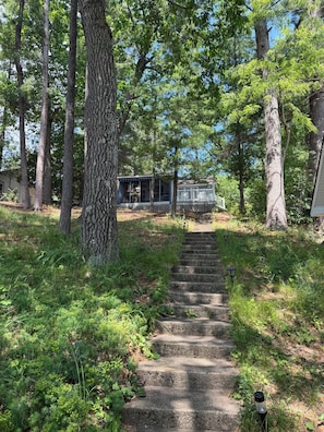 A wooden staircase leading to a cabin surrounded by trees.