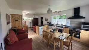 A modern kitchen with a dining area, wooden furniture, and a staircase leading to another level. - Cosy 2 bedroom  holiday apartment in a beautiful quiet area beside a lake. (Bantry)