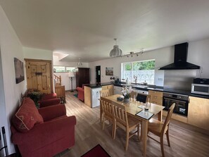 A modern kitchen with a dining area, wooden furniture, and a staircase leading to another level.