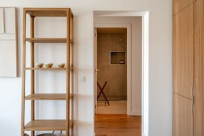 Ein Flur mit einer Holzregaleinrichtung, einer zur Kammer mit Fliesenboden führenden Tür und einem Holzschrank.