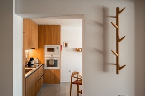 Eine moderne Küche mit Holzschränken, einer Mikrowelle, einem Backofen und einem Stuhl.