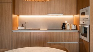 Une cuisine moderne dotée de meubles en bois, d’un four à micro-ondes encastré, d’une machine à café et d’un grille-pain.