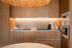 Eine moderne Küche mit Holzschränken, integriertem Mikrowellenherd, einer Kaffeemaschine und einem Toaster.