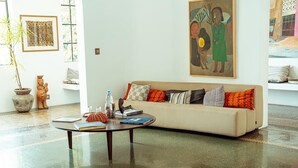 A living room with a sofa, a coffee table, a potted plant, a statue, and a painting on the wall. - Le Séku bi (Dakar)