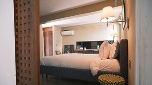 Ett hotellrum med en säng, ett litet runt bord, en vägglampa och en tv.