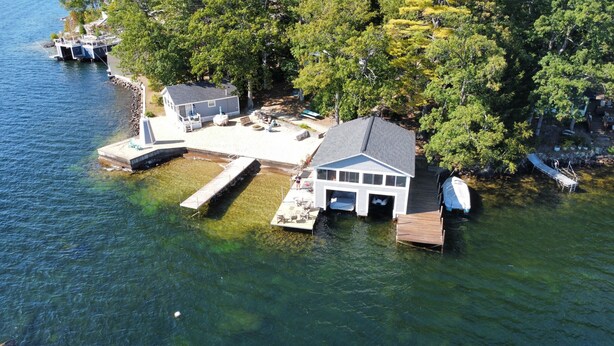 A houseboat with a dock, a small deck, and a covered area. - STAY ABOVE THE WATER ON BEAUTIFUL LAKE WINNIPESAUKEE (Laconia)
