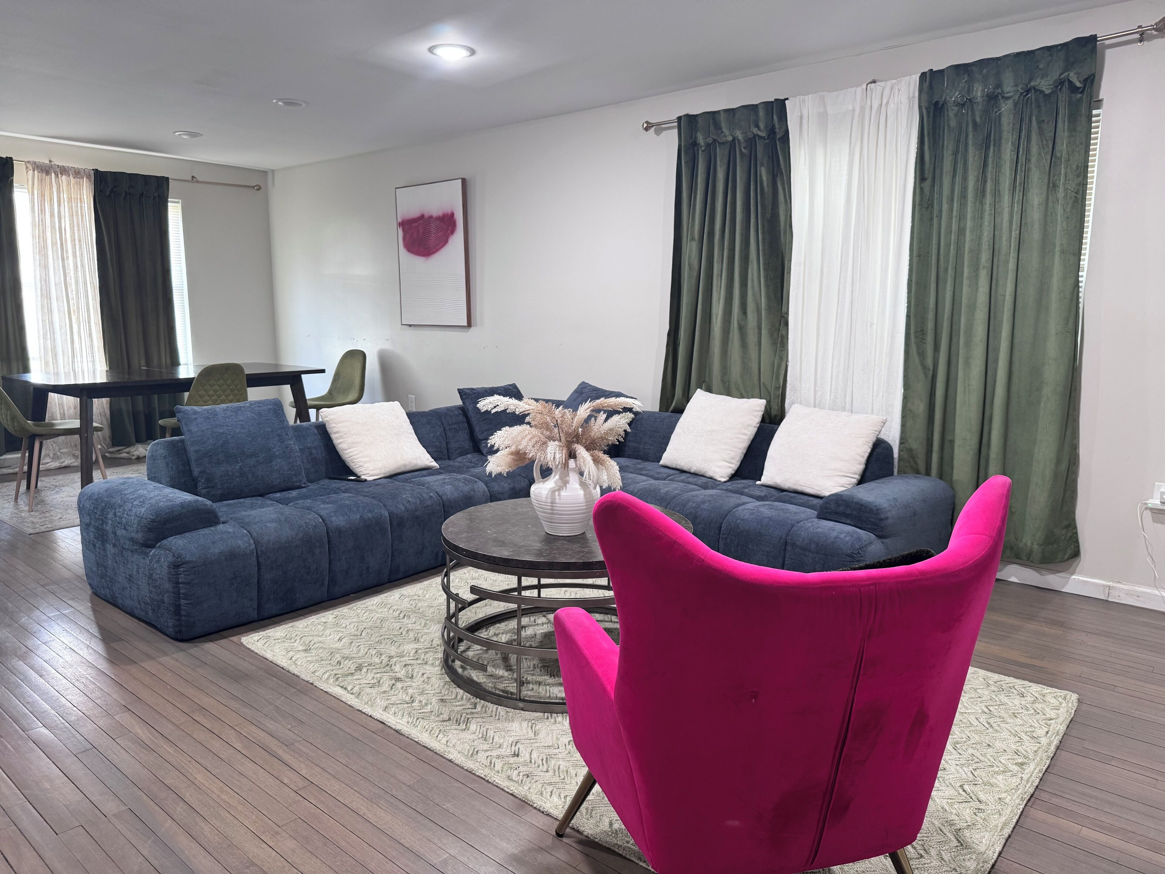 Uma sala de estar moderna com um sofá azul, uma mesa de centro redonda e uma poltrona rosa vibrante.