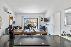 A modern dining area with a large table, chairs, and a central island with a built-in induction cooktop. - Morgan Residences 607 @ Boutique Hotel With Pool, Gym & Spa (Cabo San Lucas)