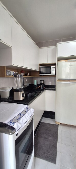 Eine moderne Küche mit weißen Schränken, einer Mikrowelle, einem Kühlschrank, einem Toaster und einem Wasserkocher.