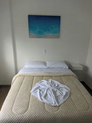 Ein Bett mit einer strukturierten Matratze, einer weißen Decke und einem Handtuch darauf.