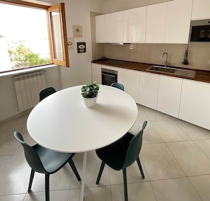A modern kitchen with white cabinets, a wooden countertop, and a round table with chairs.