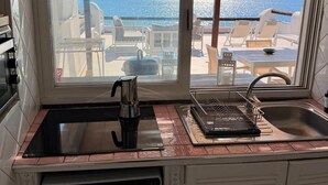 A kitchen with a view of the sea, a coffee maker, a sink, and a washing machine. - SEA VIEW apartment OCEAN Cava dell'isola • Elowen (Forio)
