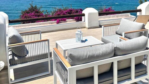 A deck with outdoor seating, a view of the sea, and some flowering plants. - SEA VIEW apartment OCEAN Cava dell'isola • Elowen (Forio)