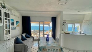 A modern interior with a dining area, kitchen, and a view of the sea.
