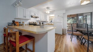 Une cuisine avec des meubles blancs, un îlot central en bois et un coin repas avec des chaises.