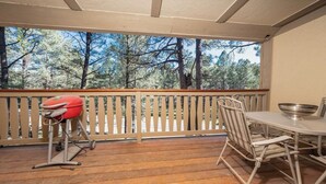 Un espace extérieur abrité, doté d’une terrasse en bois, d’un barbecue et d’une table avec des chaises.