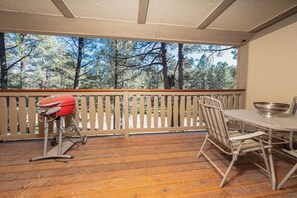 Ein überdachter Außenbereich mit Holzdeck, Grill und Tisch mit Stühlen.