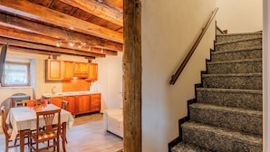 A kitchen with wooden cabinets, a dining table with chairs, and a staircase with granite steps. - Casa Daisy with direct beach access, AC and Wifi (Dervio)