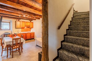 Eine Küche mit Holzausstattung, einem Esstisch mit Stühlen und einer Treppe mit Granitschritten.