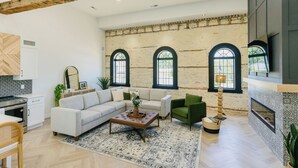 Un grand salon comprenant un canapé, des fauteuils, une table basse et une cheminée.