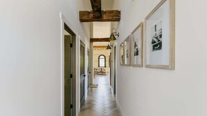 Un couloir doté d’un plancher en bois, de murs blancs et de tableaux encadrés.
