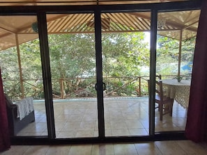 A room with a sliding glass door leading to an outdoor patio with a tiled floor and a wooden pergola. - Casas New Caribe Point (Cahuita)