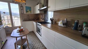 A modern kitchen with a stove, oven, and a dining area with a table and chairs. - Bright apartment with balcony in Ajaccio (Ajaccio)