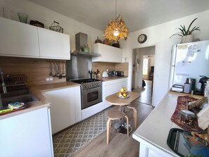 A modern kitchen with a stove, oven, and various appliances. There is a dining area with a table and chairs. - Bright apartment with balcony in Ajaccio (Ajaccio)