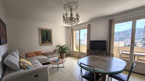 A living room with a sofa, a coffee table, a TV, and a balcony with a view. - Bright apartment with balcony in Ajaccio (Ajaccio)