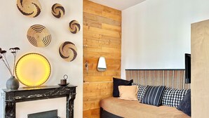 Quarto com cama, luminária na parede, lareira e pratos decorativos.