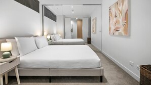 Ett modernt hotellrum med en stor säng, sängbord och konstverk på väggarna.