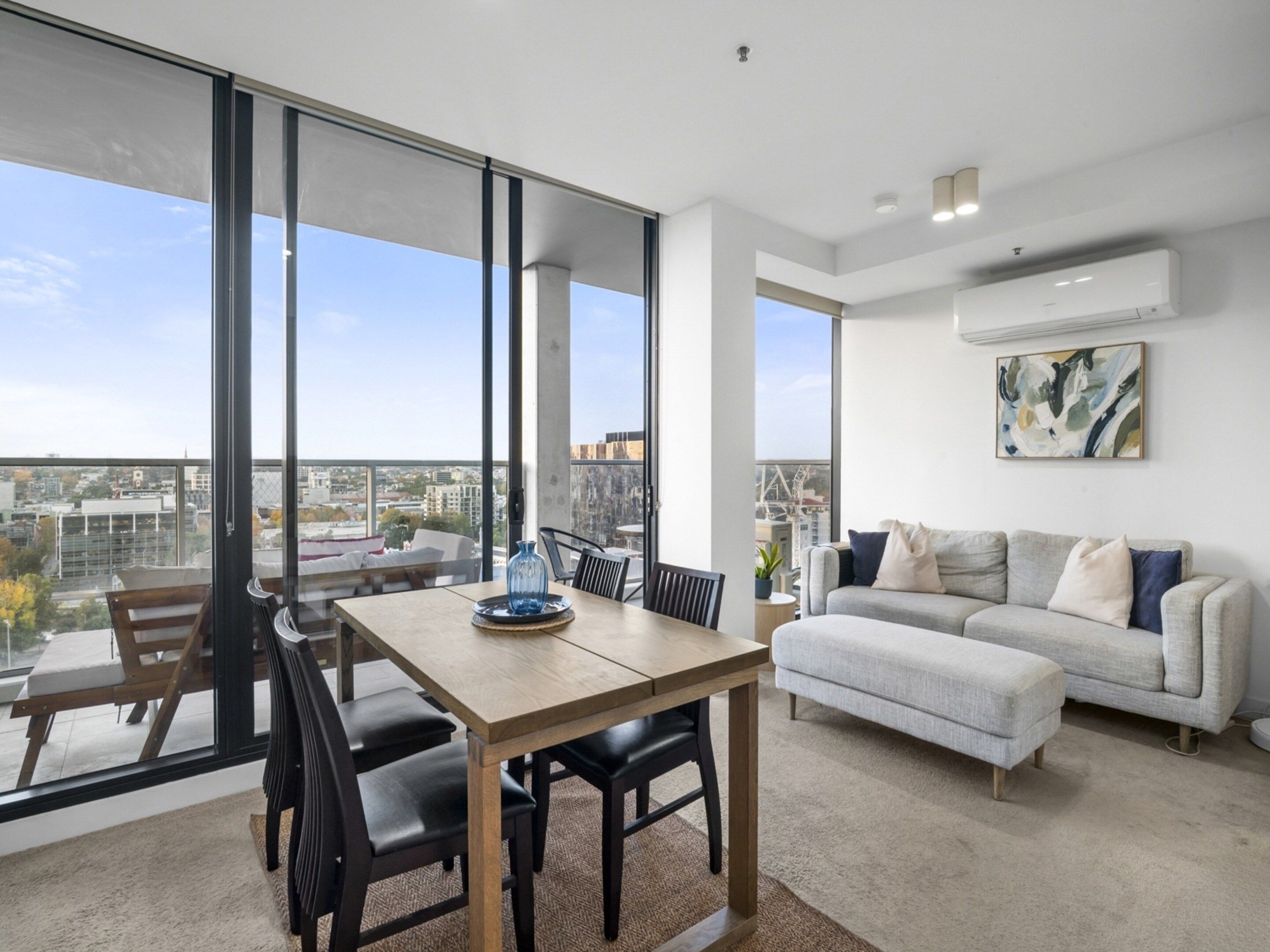 Een moderne woonkamer met een eetgedeelte, grote ramen en uitzicht over de stad.
