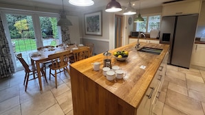 A modern kitchen with a wooden island, pendant lights, and a view of the garden. - A charming English country home set in a beautiful village 28 miles from London! (Penn)