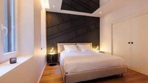 A modern bedroom with a bed, bedside tables, a window, and a wardrobe.