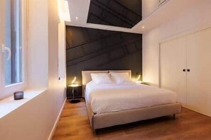 Ein modernes Schlafzimmer mit Bett, Nachttischen, einem Fenster und einem Kleiderschrank.
